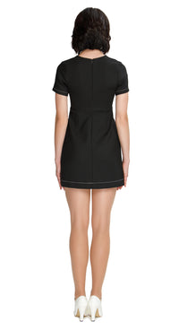 Discover the elegance of our versatile 1960s mod style Little Black Dress, featuring short sleeves and the option for 3/4” sleeves. With a rounded neckline, flattering cutout and exquisite white oversized flower buttons accented by contrasting heavy topstitching, this classic piece is a must-have for any special occasion. Its flattering silhouette and slip-into rear zip closure make it suitable for all body types.