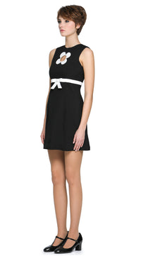 Autumn, mod style little black dress with a slight A-line, rounded neckline, detailed with a carefully sewn floral cut-out on the torso, accented by a contrasting high waist-level bow. Shown here as sleeveless, but available with alternative sleeve and hem lengths to suit preference. A simple, fun, and striking dress that's easy to reach for and pairs well with both heels and pumps.