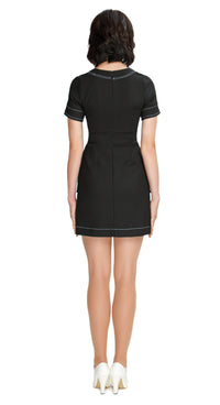 Embrace elegance with our charming mod, 60s style, Little Black Dress, featuring short sleeves (also available in ¾”). This dress boasts a rounded neckline with flattering topstitch neck detailing, extending throughout the piece, as well as deep skirt pockets and solo white flower waist level detailing.