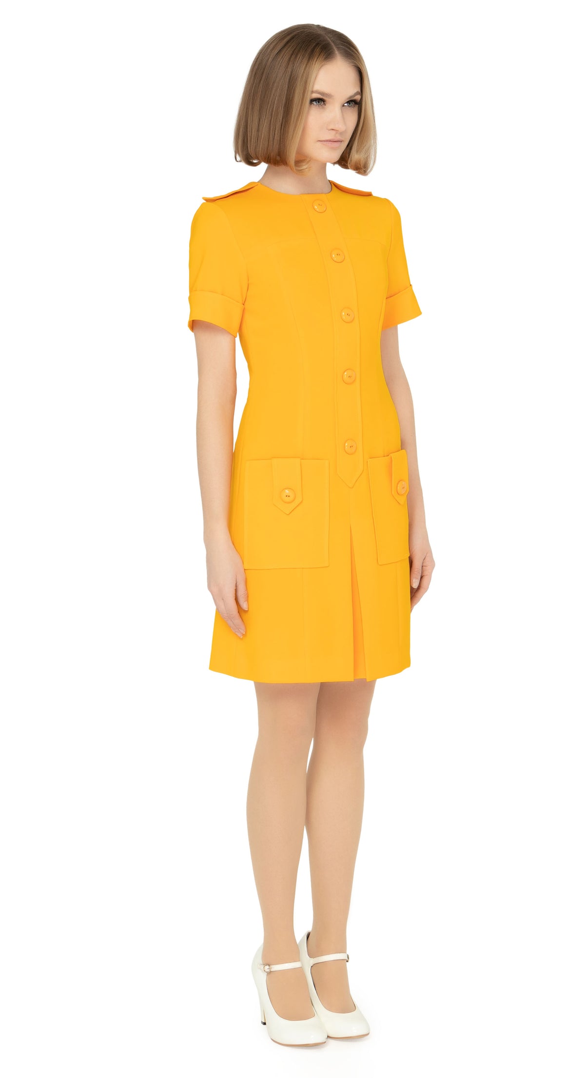 Fitted sixties cut dress with decorative five button placket, button shoulder tabs, short sleeves and functioning button tab essentials pockets with an attractive skirt pleat & immediately striking detailing throughout the bold bright orange Spanish fabric. An entrance maker for all functions, dressed to the nines with heels or casual and cool with kicks or flats.  Please choose bespoke to alternate sleeve or hem length.  Available in various colours. Please contact us for more information.