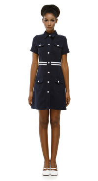 Woman wearing a navy dress with white buttons on a white background