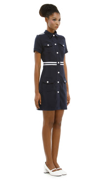 Woman wearing a navy dress with white buttons on a white background