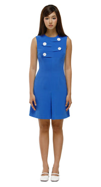 Woman wearing a blue dress with white buttons on a white background