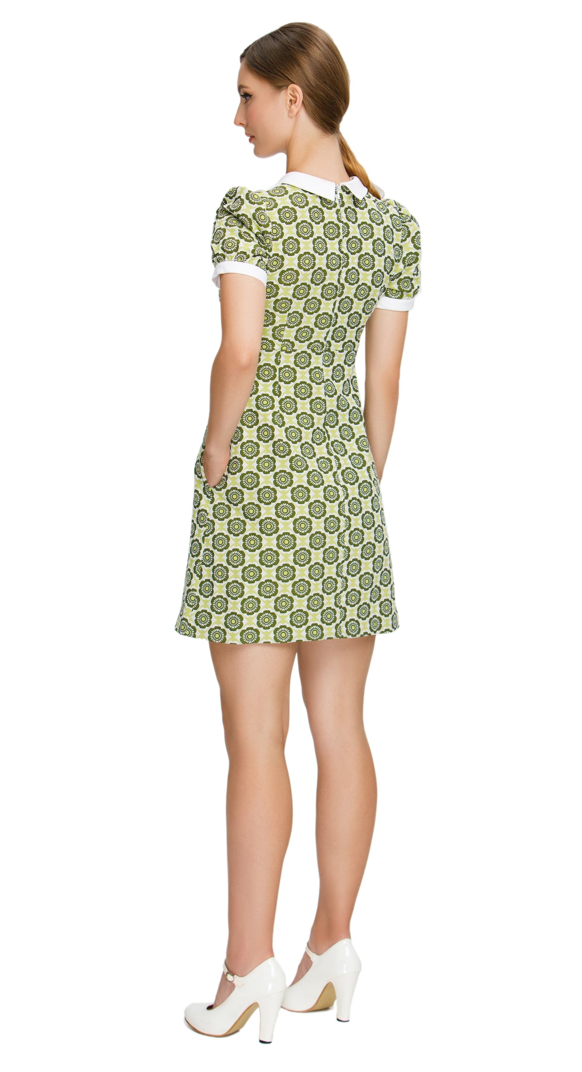 Fitted sixties style, shades of green floral,  a-line dress; a versatile piece suitable for both work and play. This dress features a charming floral pattern in various shades of green, exuding a delightful retro vibe. The style features a white bib offset by a 4-button-detailed tab, slightly puffed short sleeves, and functional side pockets, adding a touch of timeless elegance and practicality to the ensemble.