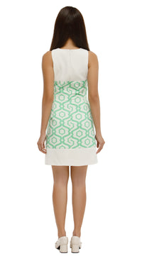 Woman wearing a white sleeveless top and green patterned skirt on a white background