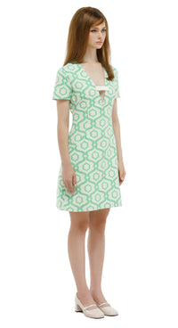 Woman wearing a green patterned dress on a white background