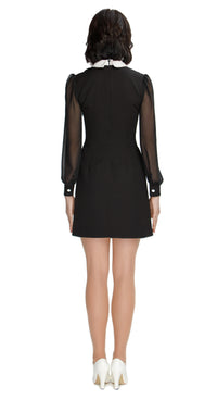 Shop our Autumn 60s style Classic Little Black Dress with flattering sheer sleeves, fitted cuffs, and a contrasting white collar. This chic dress boasts a flattering silhouette, making it the perfect choice for any special occasion this season. Elevate your autumn fashion with timeless elegance.