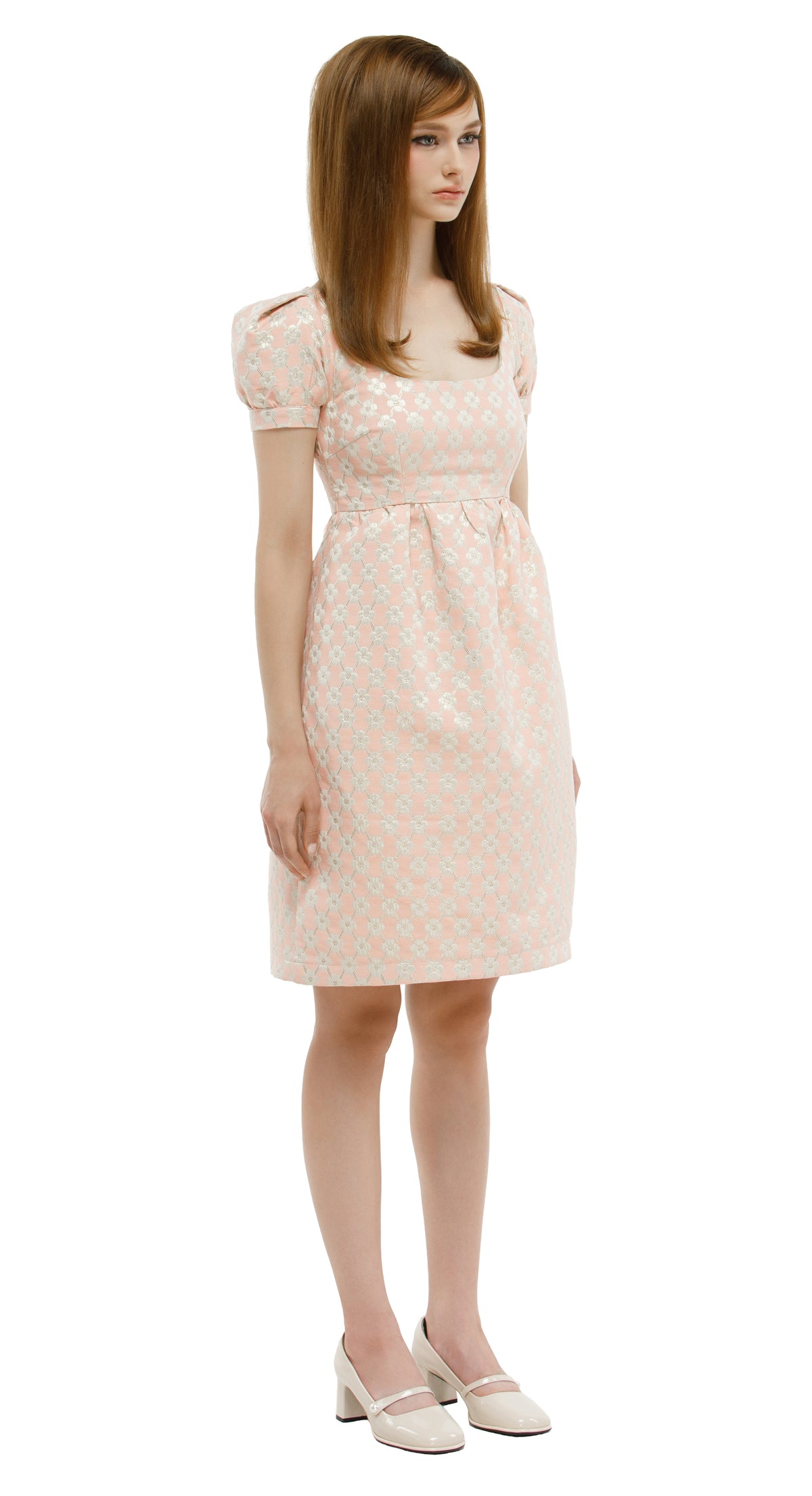 Woman wearing a rose coloured 1960s inspired babydoll dress  on a white background.