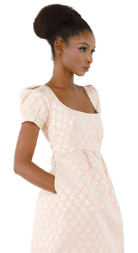 Woman wearing a rose coloured 1960s inspired babydoll dress  on a white background.