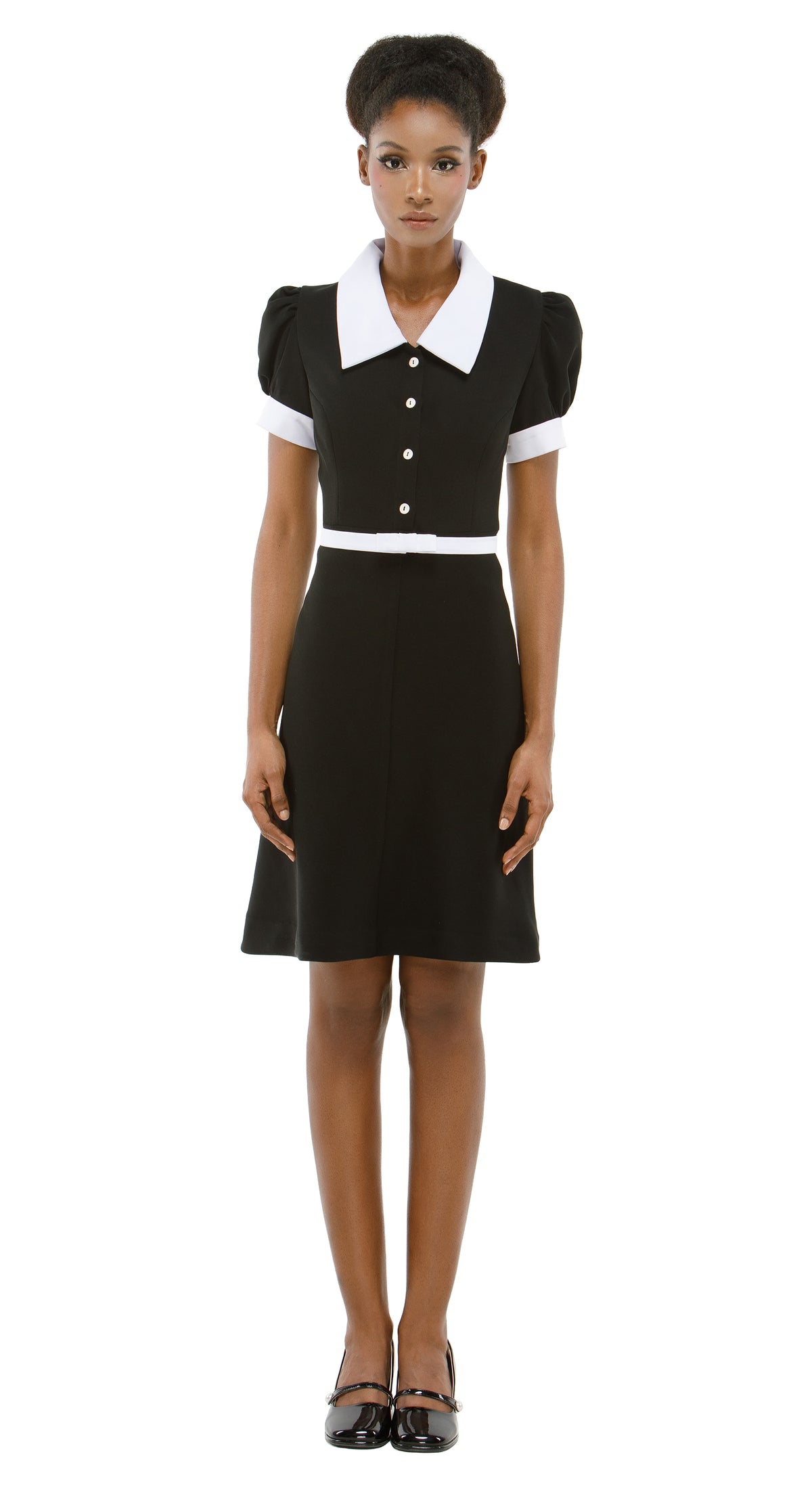 Woman wearing a black dress with white collar and cuffs on a white background