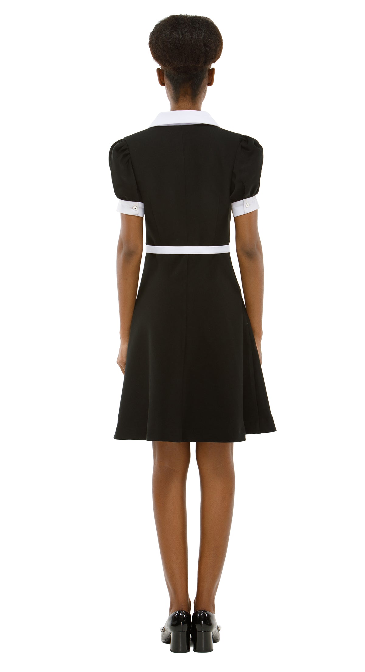 Black dress with white accents worn by a model on a white background