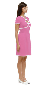 Woman wearing a  Mod 1960s style pink dress with white accents, 2 diamond cutouts and 2 small bows on a white background