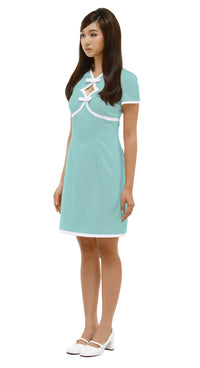Woman wearing a  mint green, Mod 1960s style dress with white accents, 2 diamond cutouts and 2 small bows on a white background