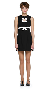 Autumn, mod style little black dress with a slight A-line, rounded neckline, detailed with a carefully sewn floral cut-out on the torso, accented by a contrasting high waist-level bow. Shown here as sleeveless, but available with alternative sleeve and hem lengths to suit preference. A simple, fun, and striking dress that's easy to reach for and pairs well with both heels and pumps. 