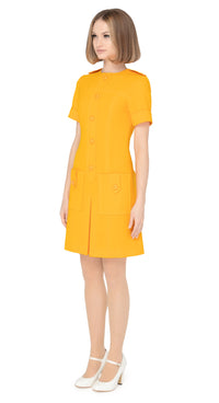Fitted sixties cut dress with decorative five button placket, button shoulder tabs, short sleeves and functioning button tab essentials pockets with an attractive skirt pleat & immediately striking detailing throughout the bold bright orange Spanish fabric. An entrance maker for all functions, dressed to the nines with heels or casual and cool with kicks or flats.  Please choose bespoke to alternate sleeve or hem length.  Available in various colours. Please contact us for more information.