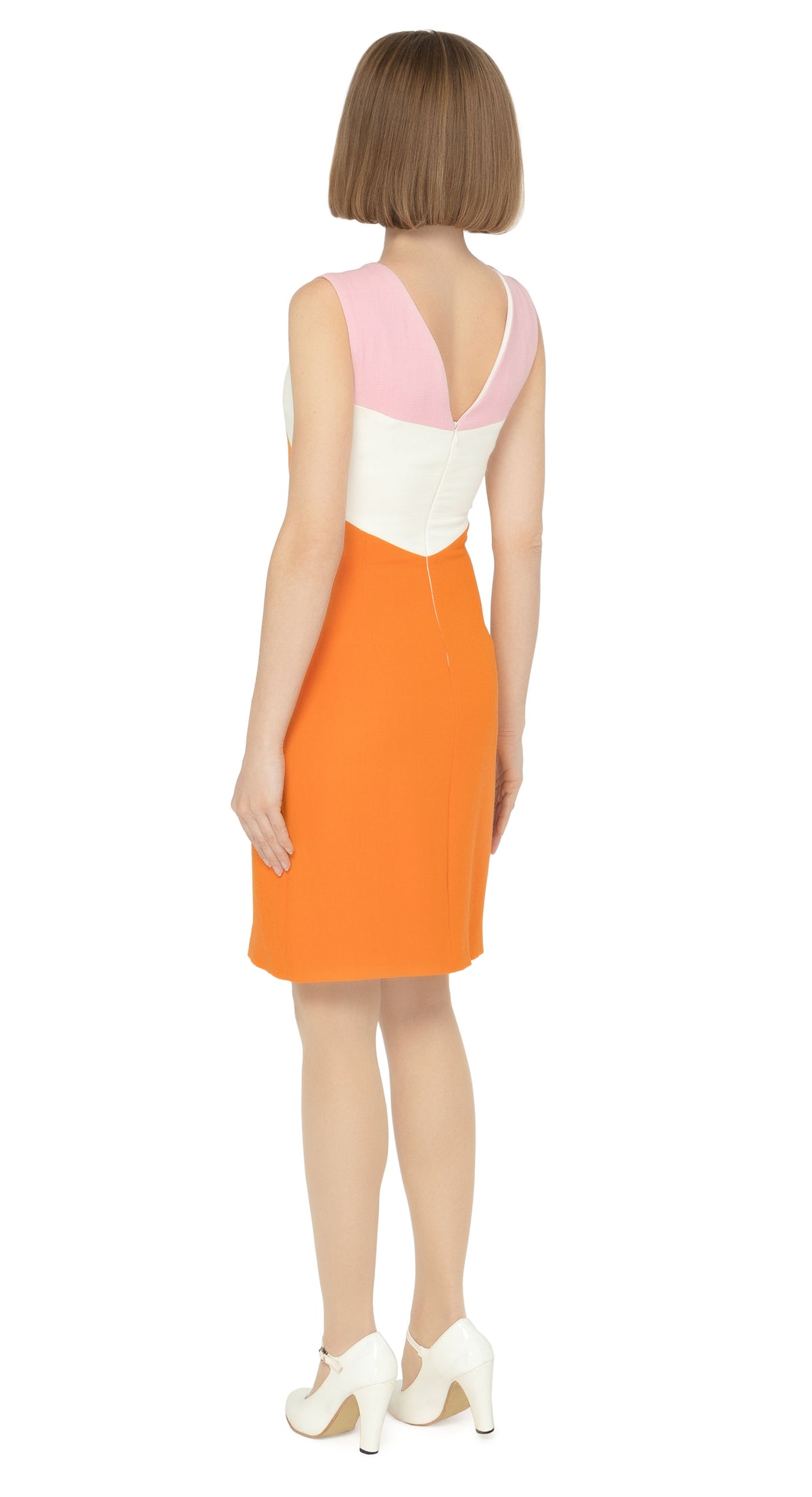 This gorgeous, sixties style dress is a perfect fit for springtime occasions. The fitted silhouette, sleeveless design, and structured pale pink shoulder panels lead to a white band and an orange body. The dress also features a feminine cutout with a dainty bow, and a v-neckline. Fully lined for comfort, this dress is sure to turn heads with its choice of flattering feminine details and easy to pair to color scheme.