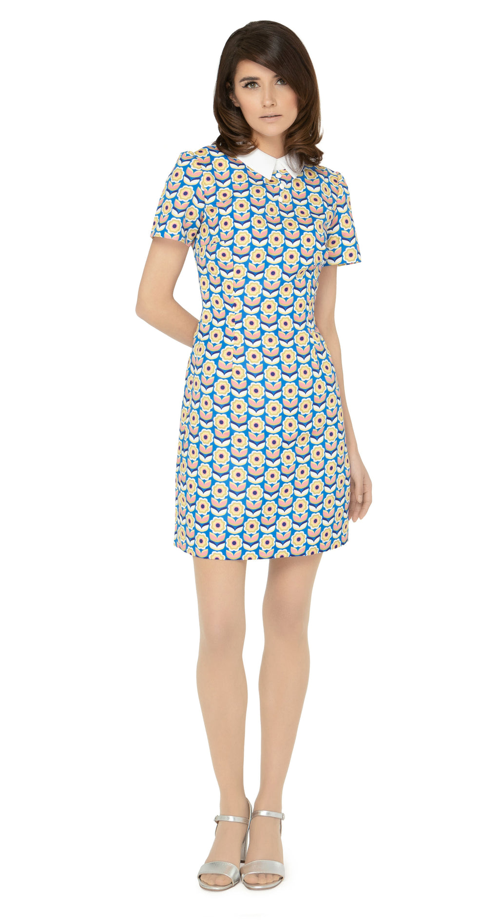 This classic, fitted sixties style spring floral dress produced in a luxury French mill weave in royal blue, pink, white, mustard yellow and navy-blue tones, with a classic stand up collar and short slightly puffed sleeves. It is designed with a zippered back closure for easy wear. The intricate detailing and exquisite craftsmanship make it a stunning piece. Perfect for a warm spring day, this dress is both stylish and comfortable.