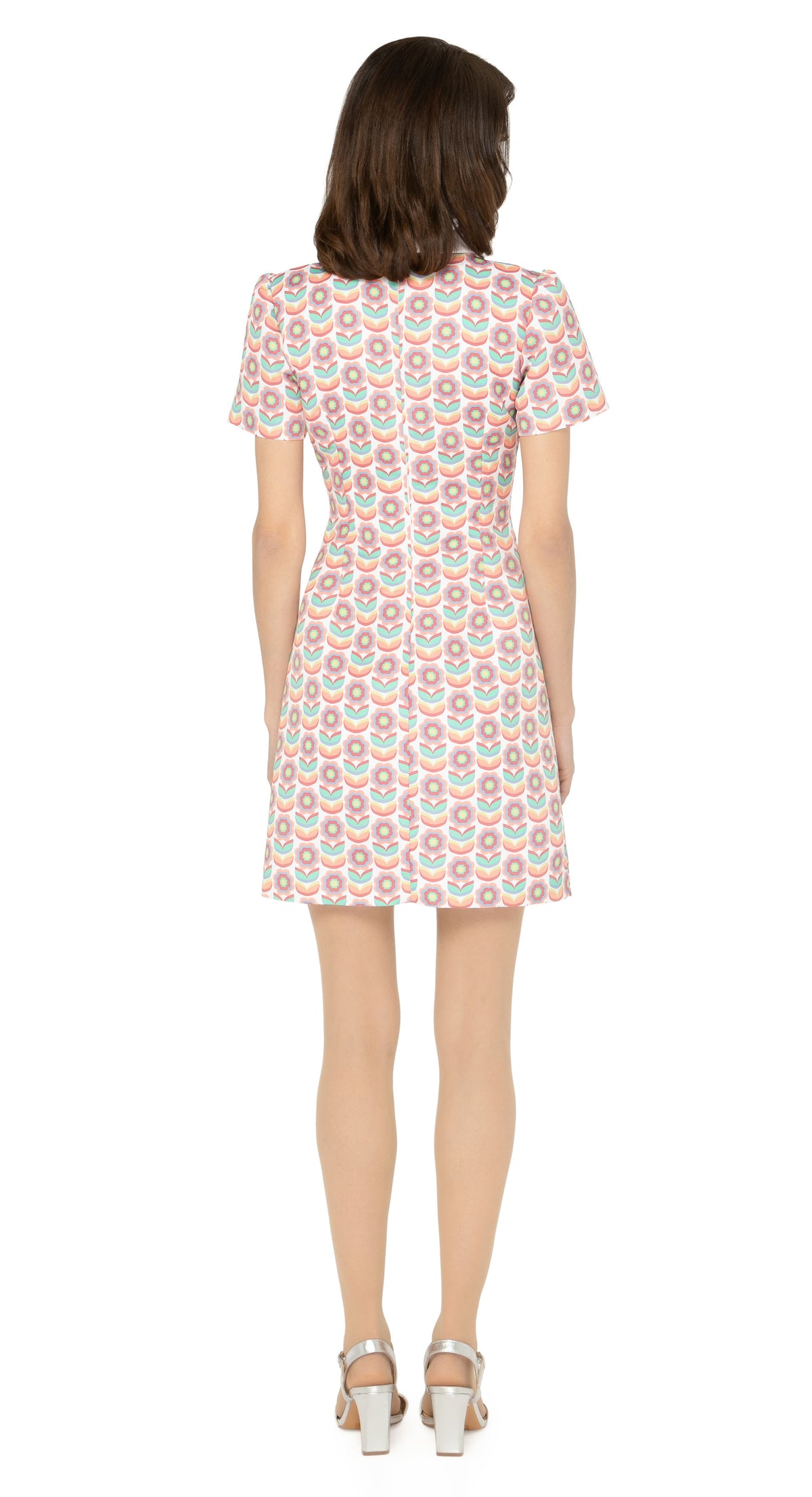 This classic, fitted sixties style spring floral fabric dress produced in a luxury French mill weave in white, peach, red, green, blue and yellow tones, with a classic stand up collar and short slightly puffed sleeves. It is designed with a zippered back closure for easy wear. The intricate detailing and exquisite craftsmanship make it a stunning piece. Perfect for a warm spring day, this dress is both stylish and comfortable.