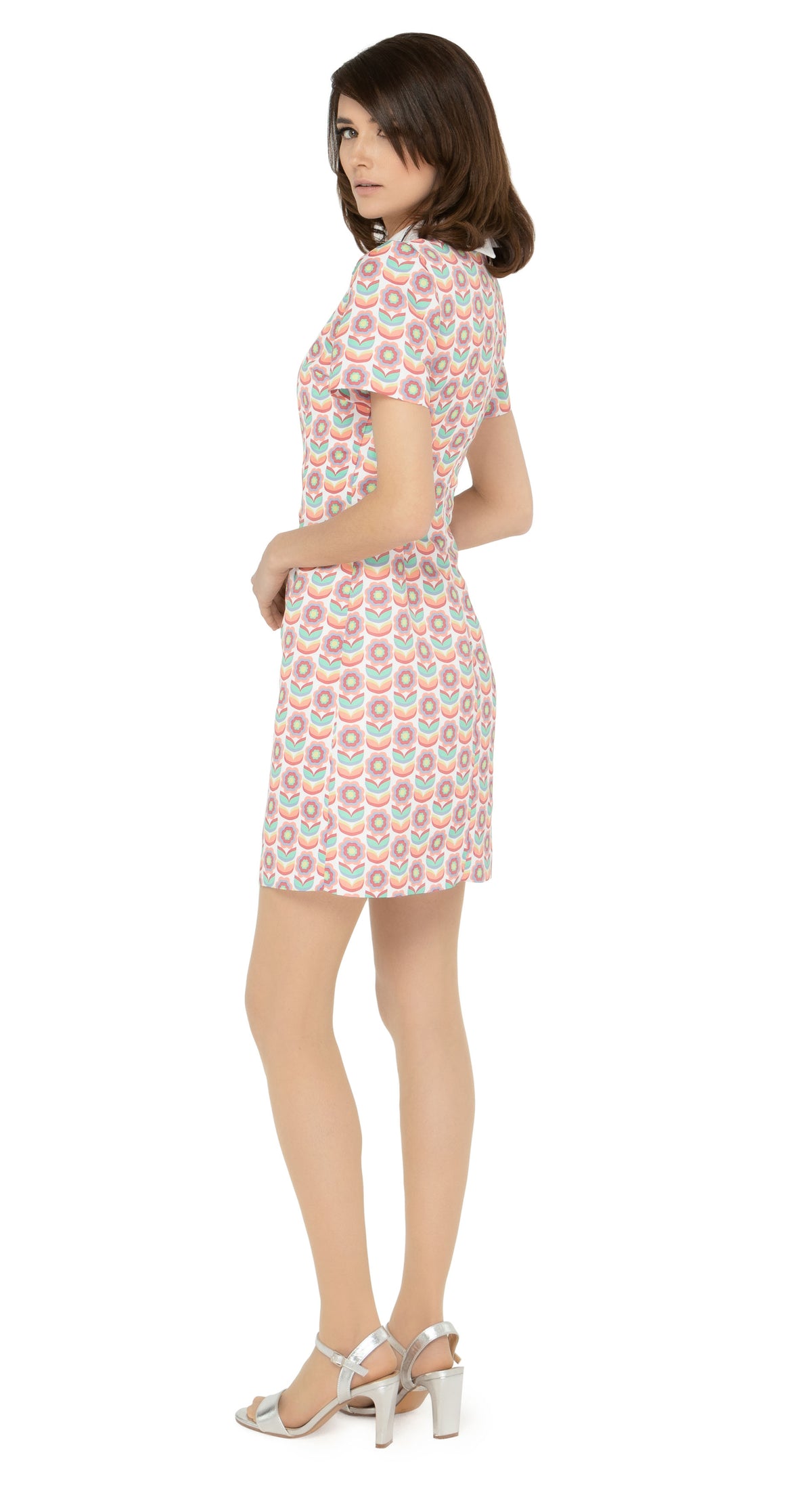 This classic, fitted sixties style spring floral fabric dress produced in a luxury French mill weave in white, peach, red, green, blue and yellow tones, with a classic stand up collar and short slightly puffed sleeves. It is designed with a zippered back closure for easy wear. The intricate detailing and exquisite craftsmanship make it a stunning piece. Perfect for a warm spring day, this dress is both stylish and comfortable.